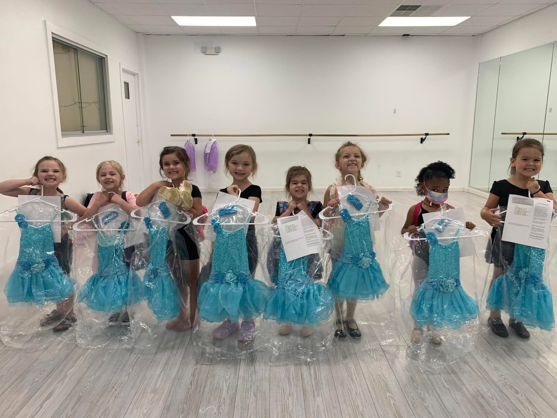 Preschool dancers proudly showing off their blue recital costumes in the studio