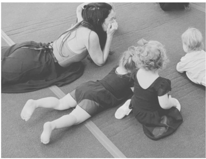 Toddlers and their grown-ups stretching together on the studio floor
